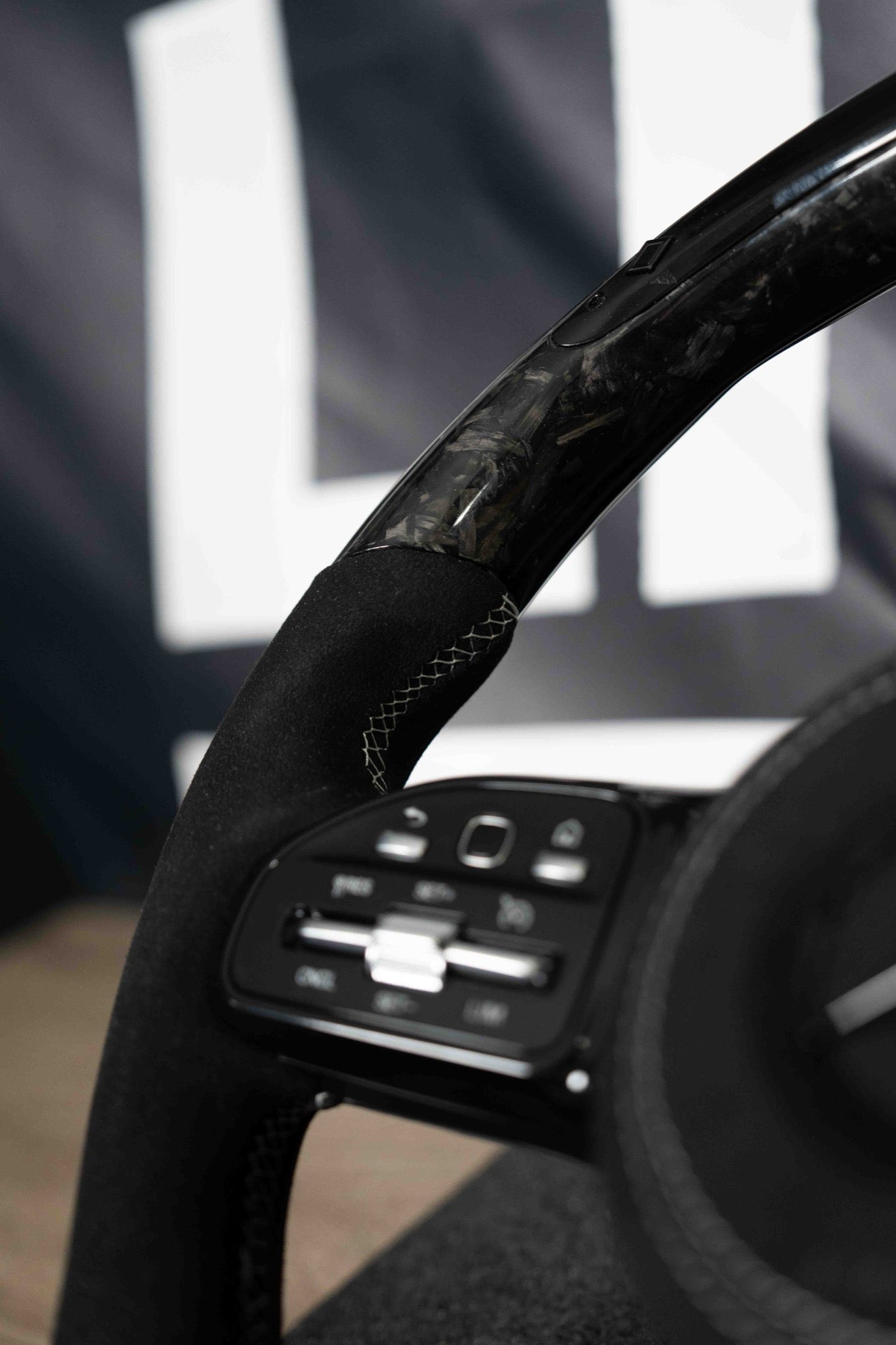 Detalle del aro en carbono forjado y costura gris cosida a mano sobre Alcantara