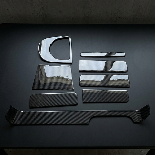 Kit interior de fibra de carbono de 8 piezas para Mercedes Clase G W463 y W464 dispuesto sobre mesa negra