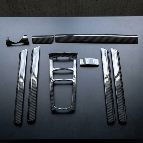 Kit interior de carbono seco de 9 piezas para Porsche Cayenne 958 dispuesto sobre mesa negra
